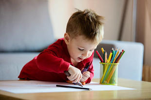 Child drawing with pencil crayons