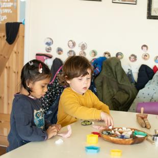 A couple of children sitting at a table playing toys.