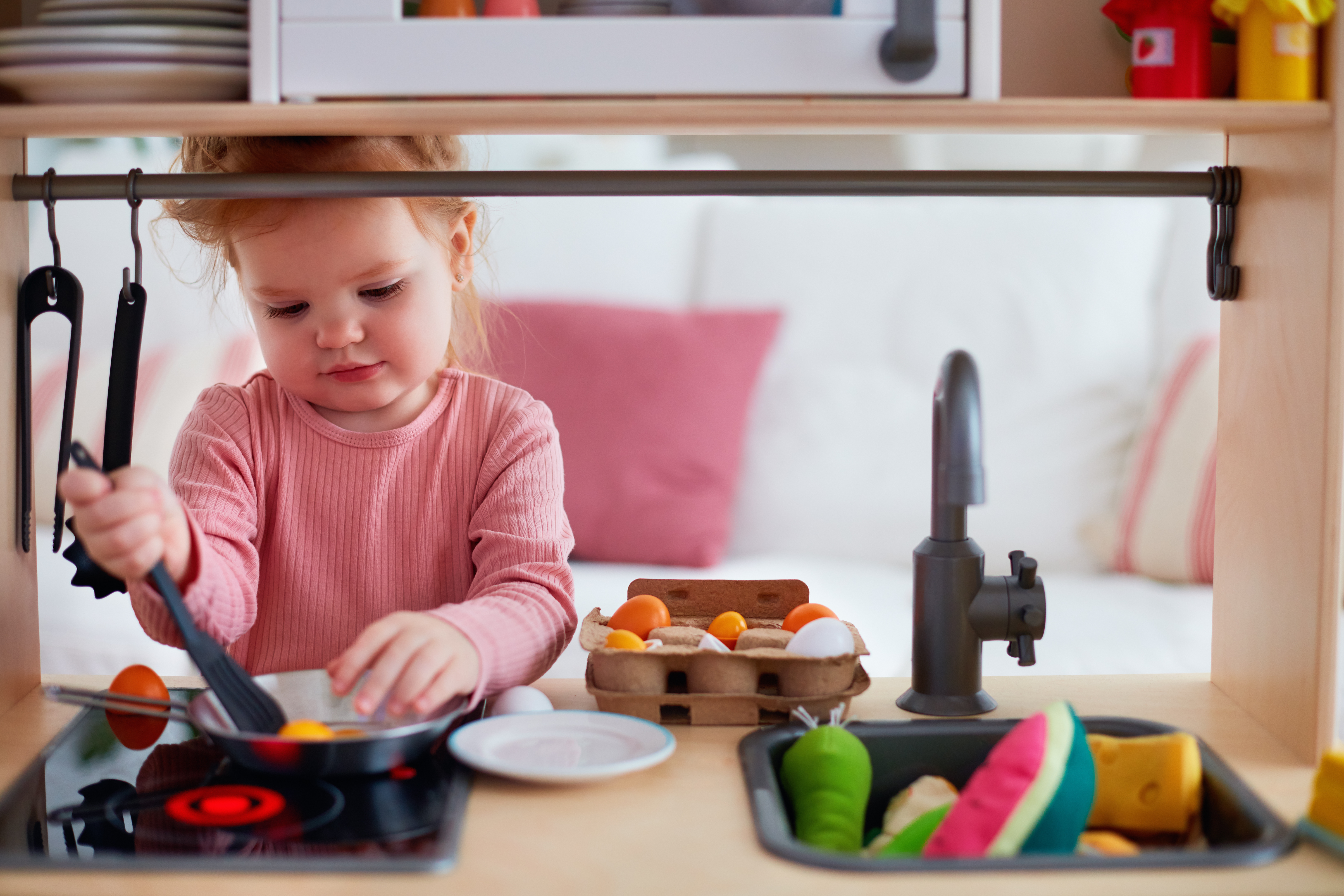 Toddler playing in a role play kitchen